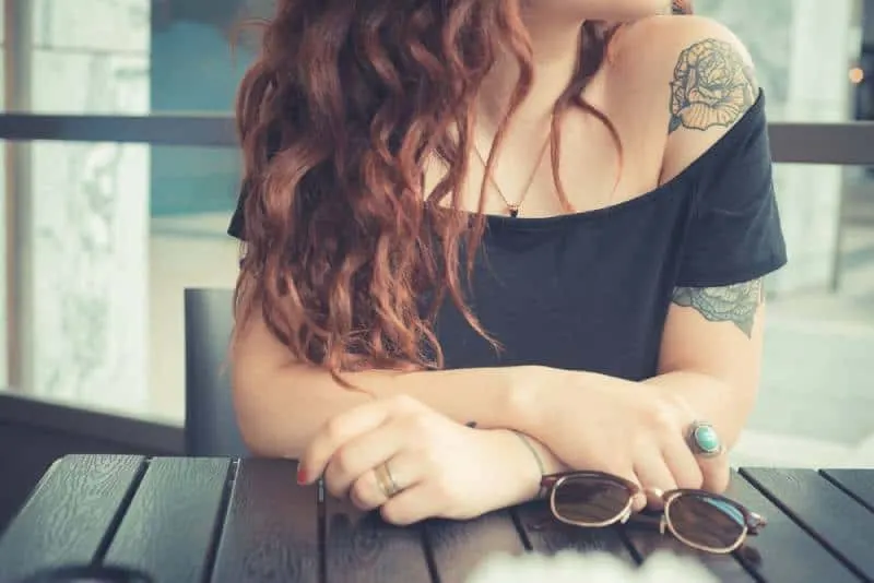 hipster woman with red curly hair and tattoo on her arm