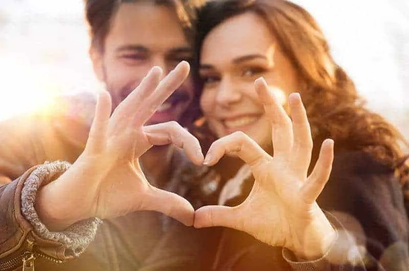 man and woman making heart sign of hands