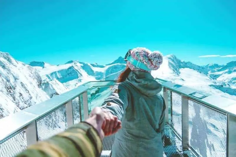 man holding woman hand on mountain