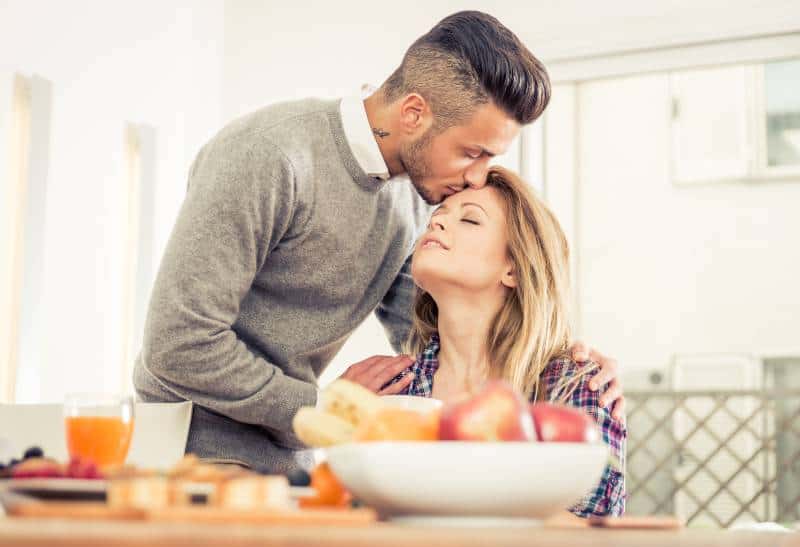 man kissing his girlfriend in forehead