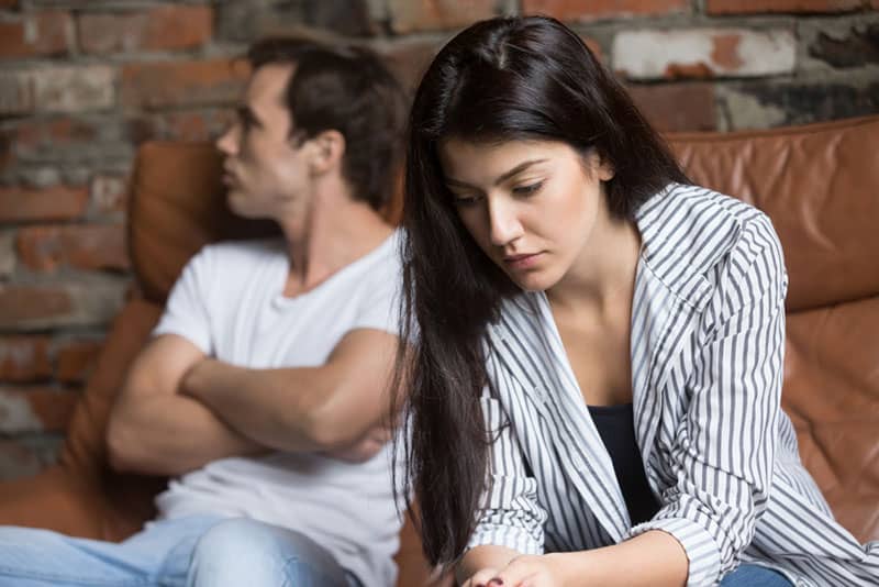 mujer triste sentada separada de su novio enfadado