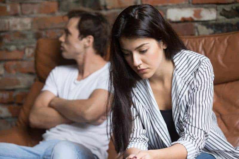 sad woman sitting next to her serious boyfriend