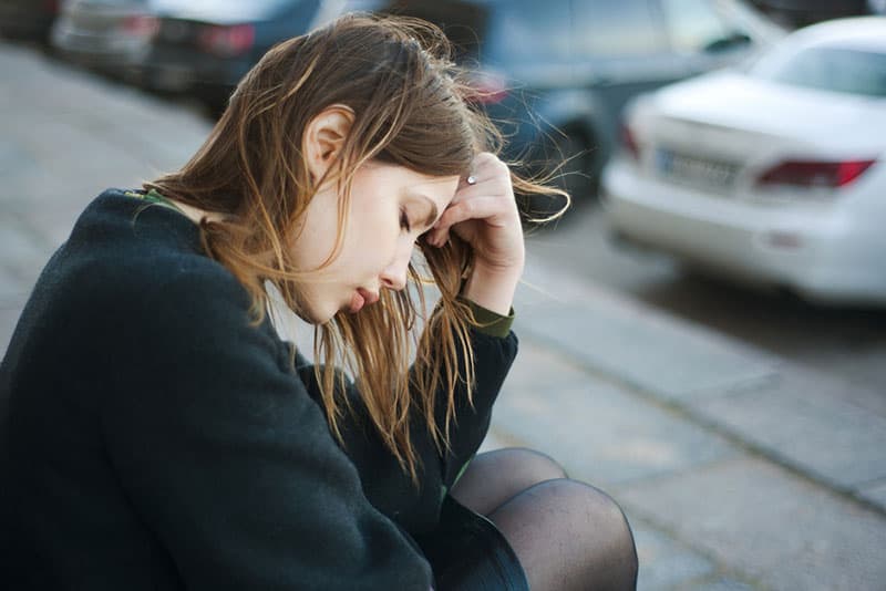 mujer triste sentada en la calle