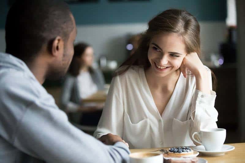 Donna timida che sorride con un uomo al bar