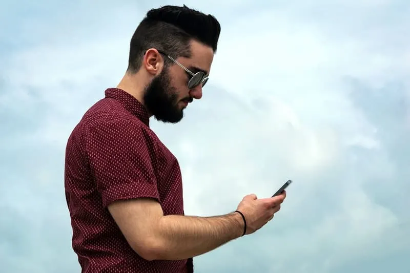 side view of man wearing eyeglasses and looking at his phone