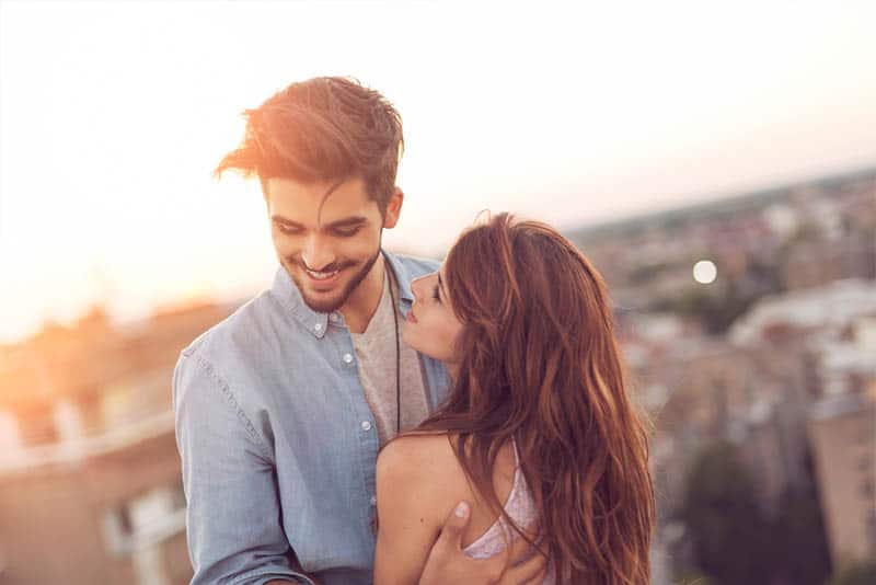 pareja sonriente se abraza al aire libre