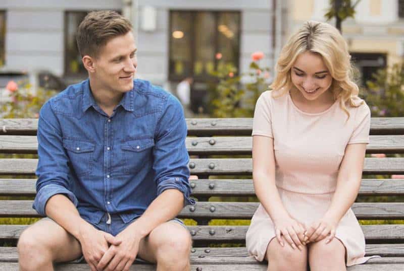 smiling man and woman sitting on a park bench