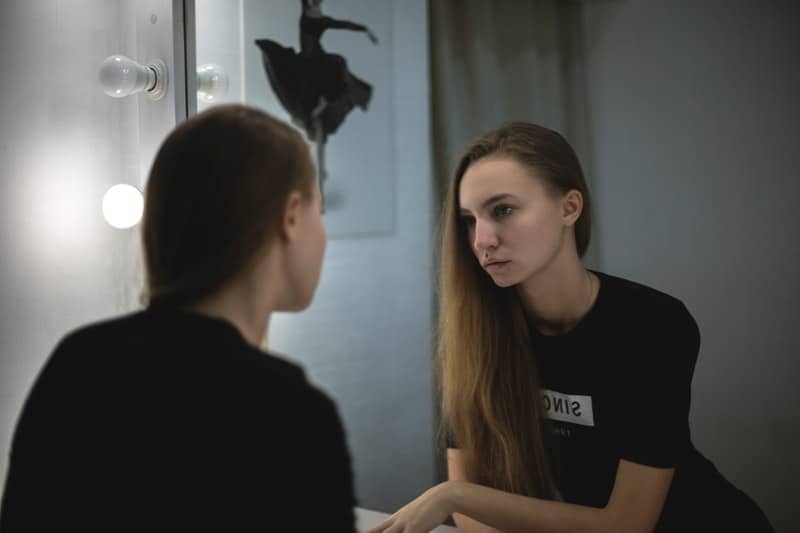 the sad girl in the toilet looks in the mirror