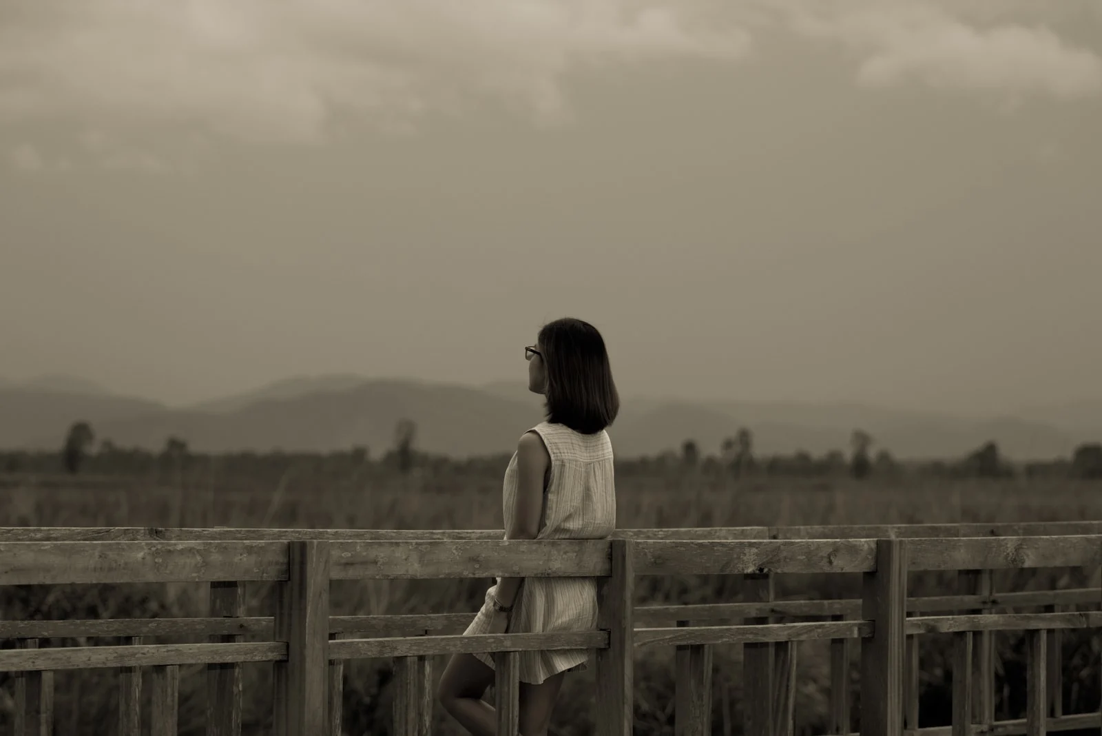 the woman stands leaning against the railing with her back turned