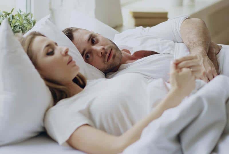 thoughtful couple lying on bed