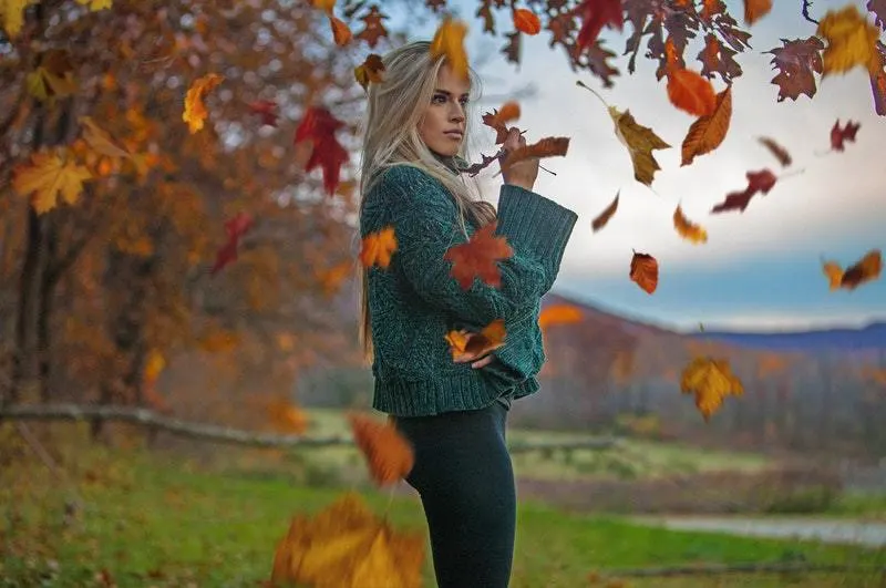 woman posing around brown leafs