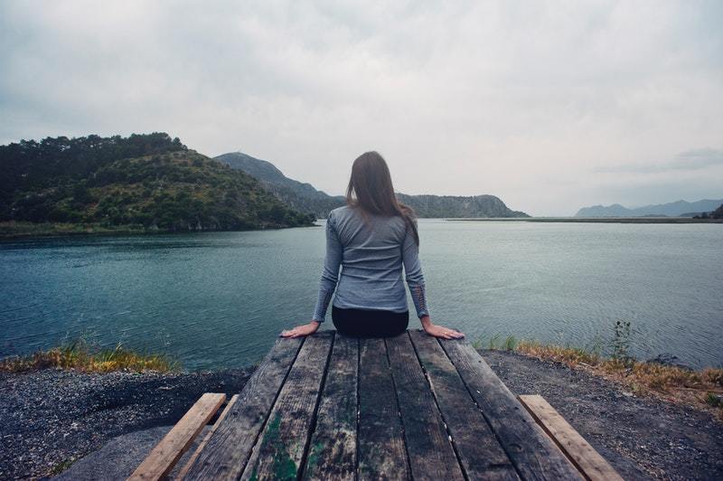 donna seduta da sola a guardare il lago