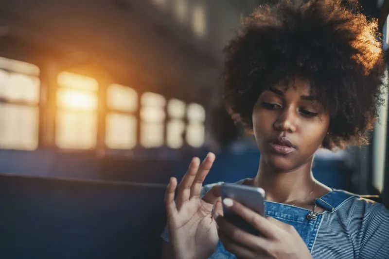 woman sitting in train holding her phone