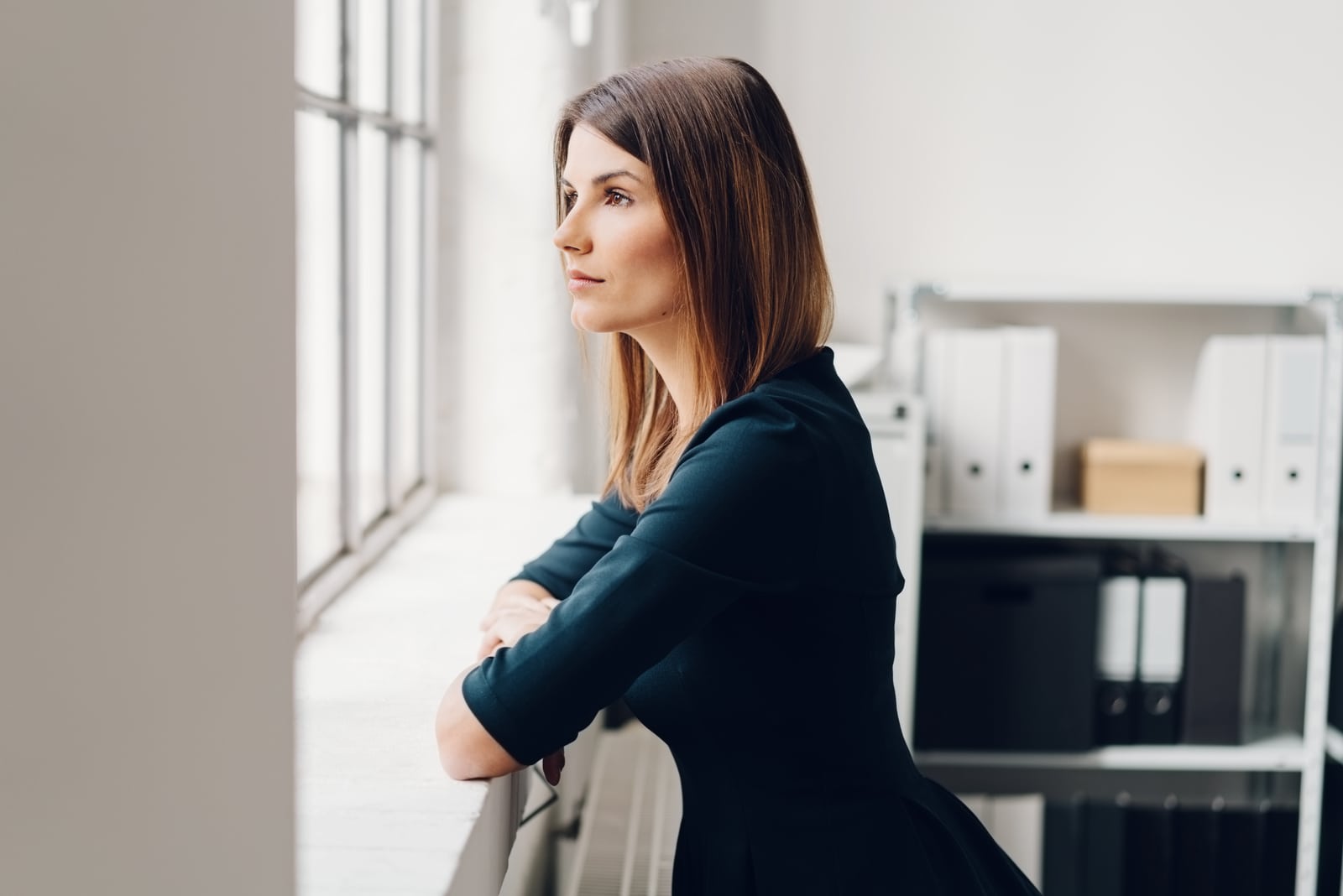 donna in piedi che guarda fuori dalla finestra