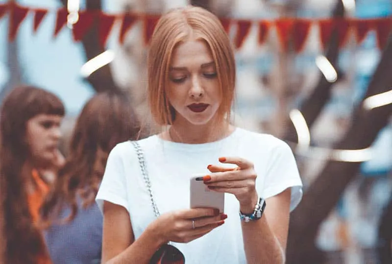 woman wearing white shirt holding her phone