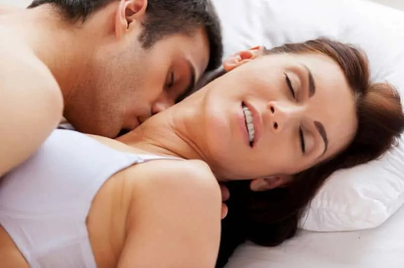 young loving couple making love while lying in bed