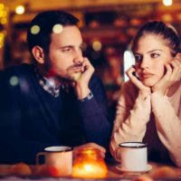 man looking at thoughtful woman in cafe