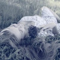 the woman is lying in the grass