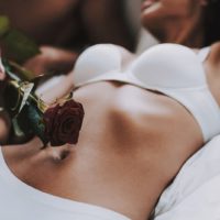 close up photo of man putting rose on woman's stomach
