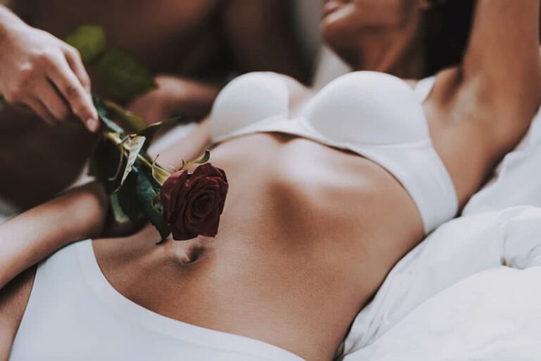 close up photo of man putting rose on woman's stomach