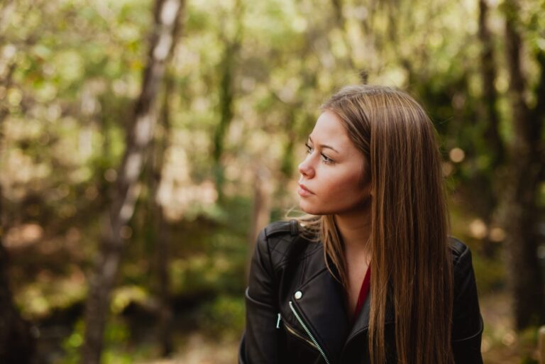 pensive woman wearing black jacket in forest