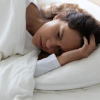 sad worried woman lying in bed