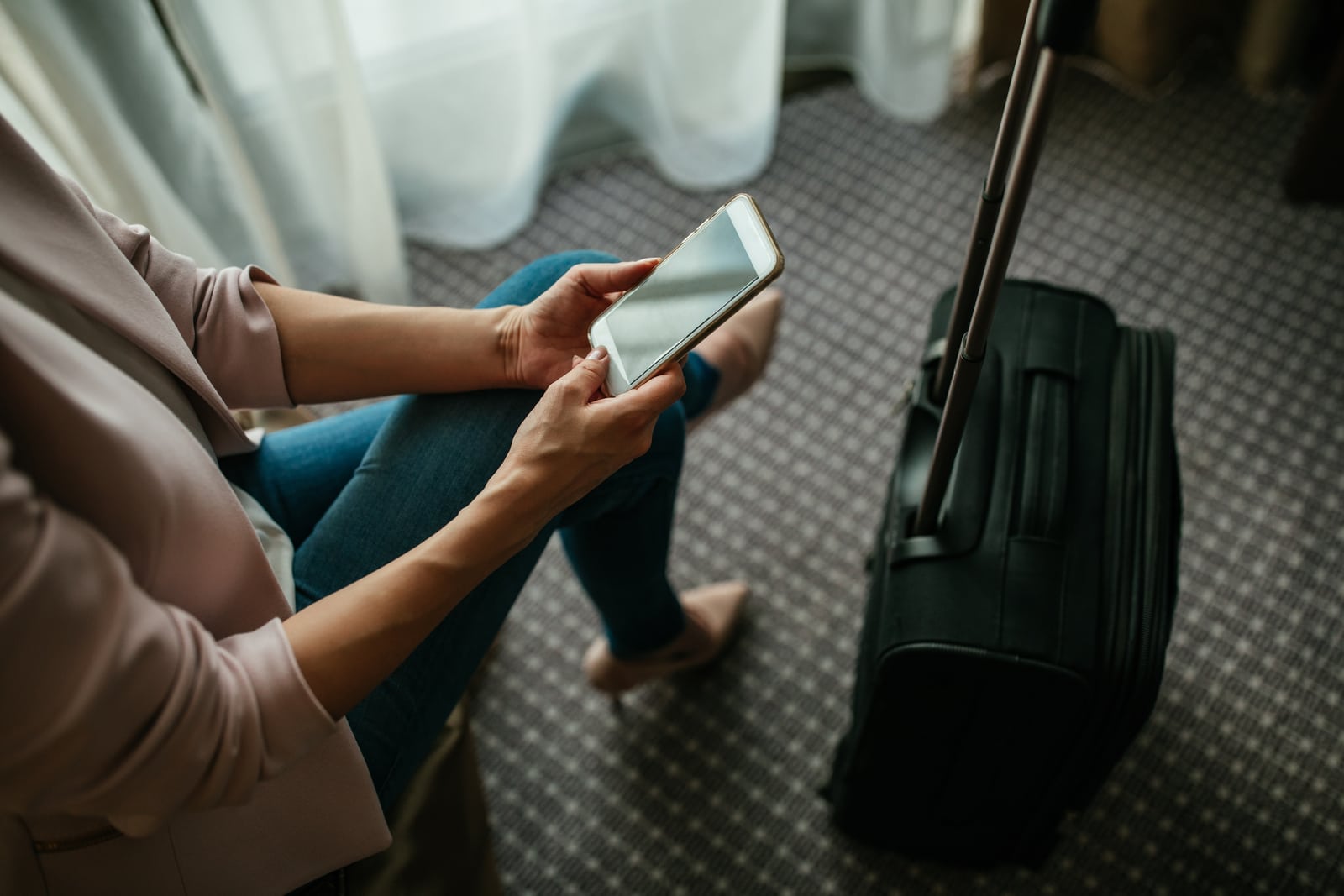 una mujer con una maleta utiliza un teléfono móvil