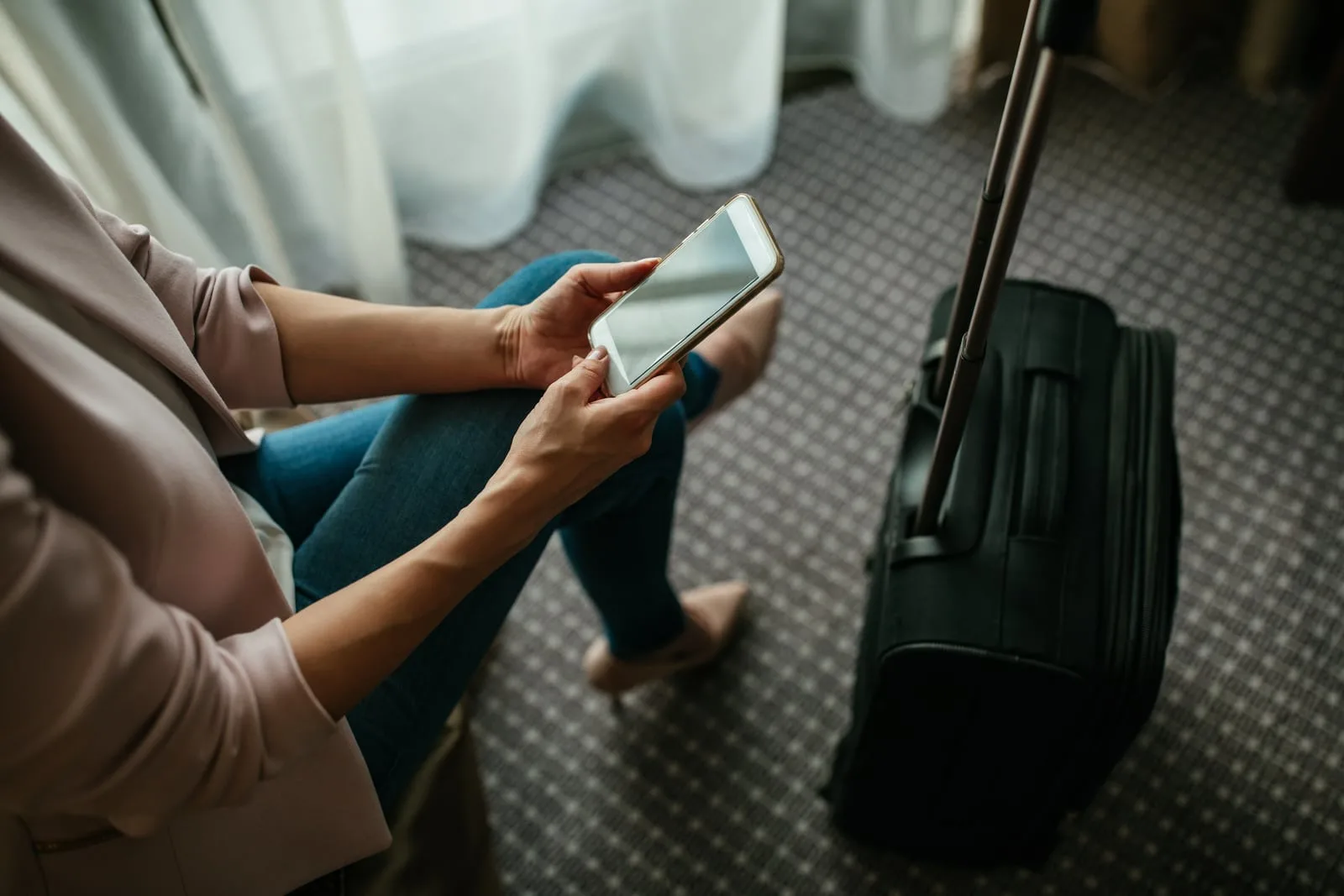 a woman with a suitcase uses a cell phone