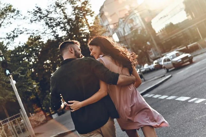 back view of couple smiling and looking each other while crossing street
