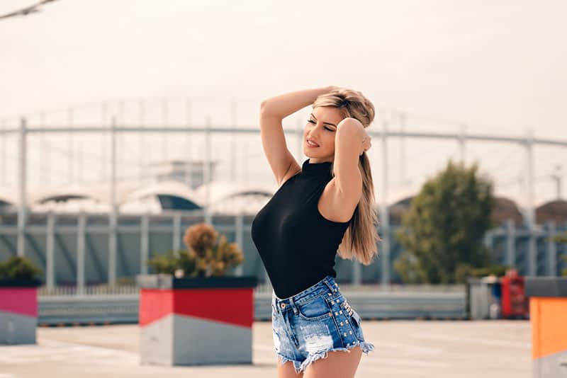 Guapa chica rubia con jeans cortos parada afuera