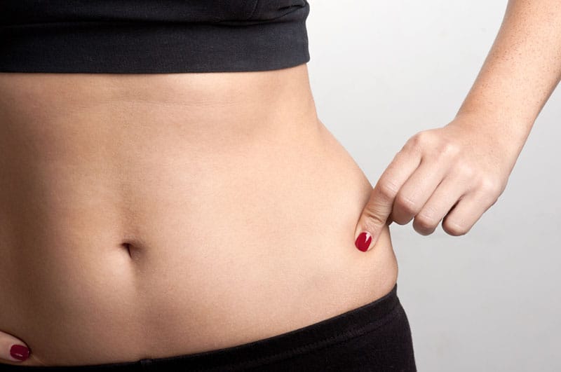 close up photo of woman holds belly fat
