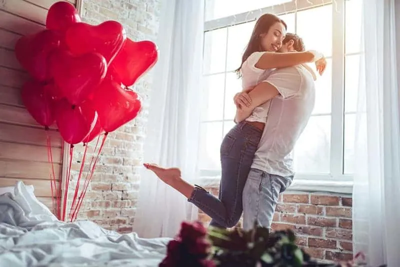 couple hugging at home beside balloons