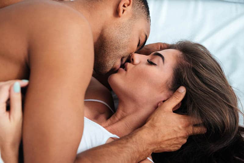 couple kissing with closed eyes in bedroom