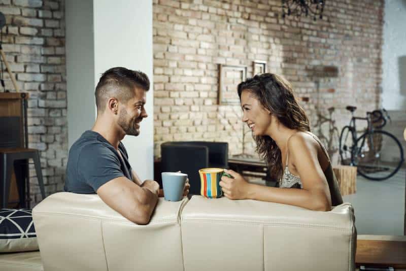 pareja sentada en el salon y hablando con cafe