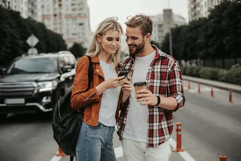 couple standing on the street watching something on phone