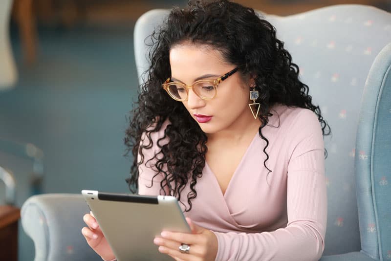 mulher de cabelo encaracolado à procura de um tablet