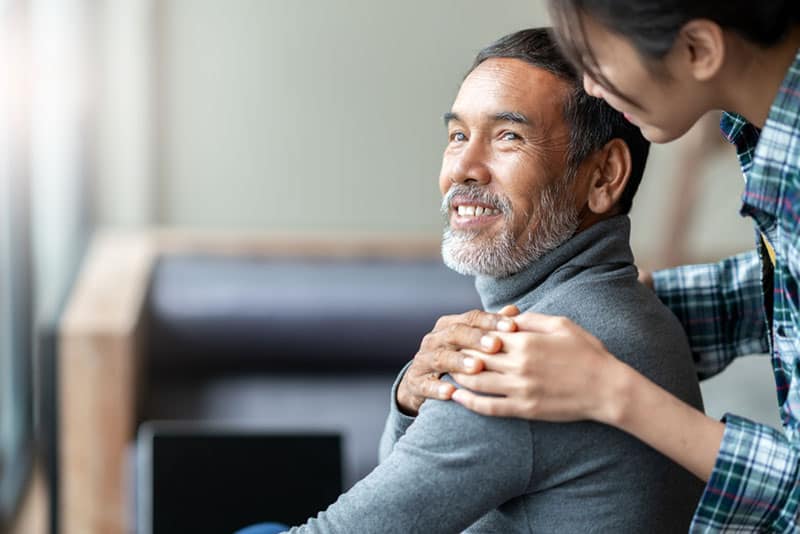 daughter holding hands on fathers shoulders