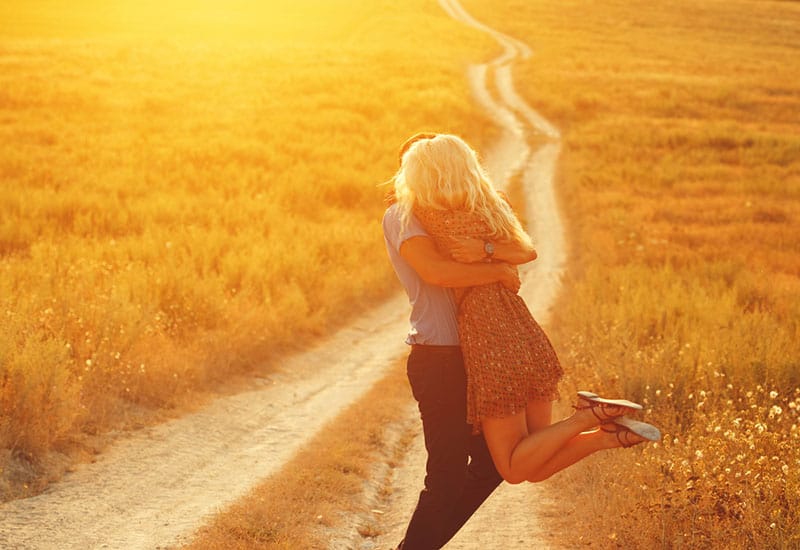 lovely couple hugging during sunset in grass field