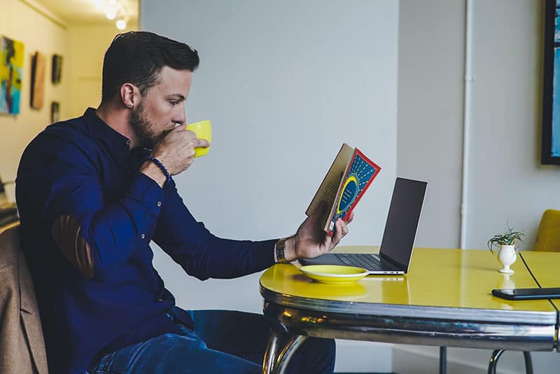 man drinking coffee and reading book