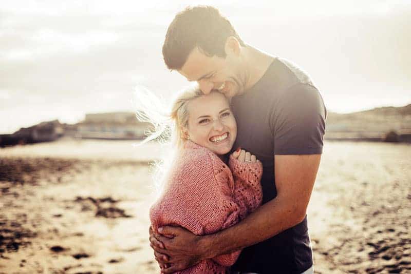 hombre abrazando mujer sonriente al aire libre