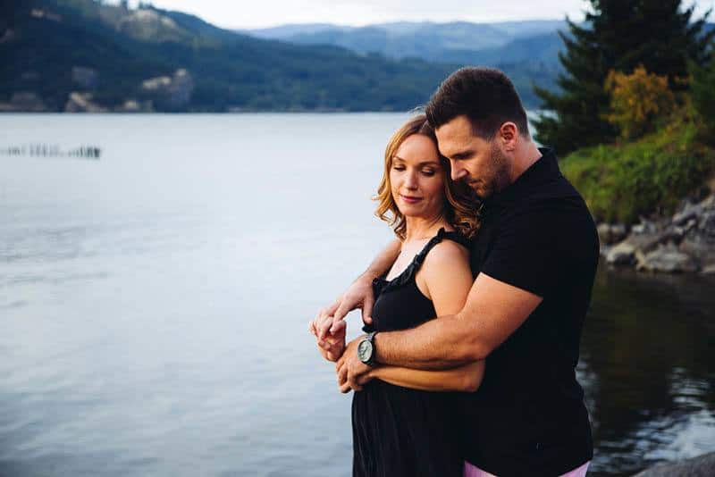 man hugging woman from back by the lake