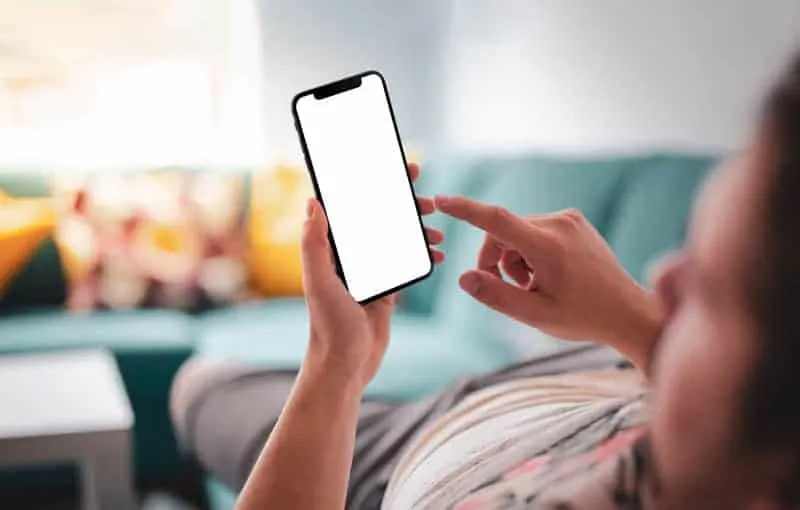 man lying on couch and looking at phone