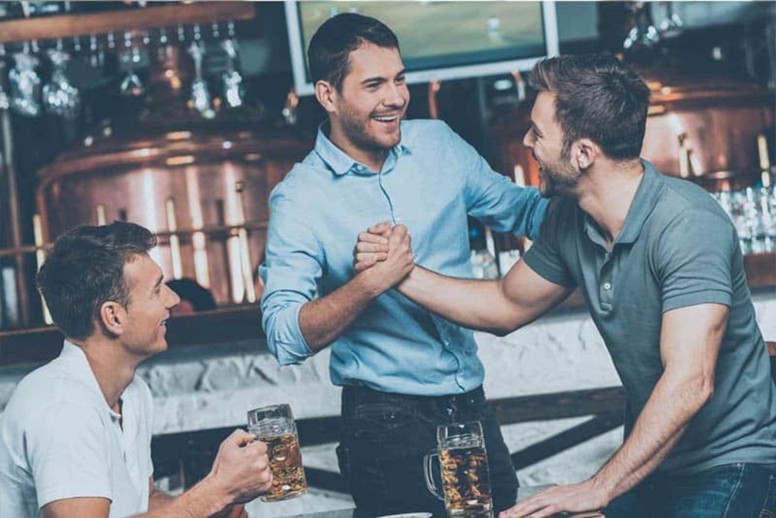 man with his friend in bar drinking beer