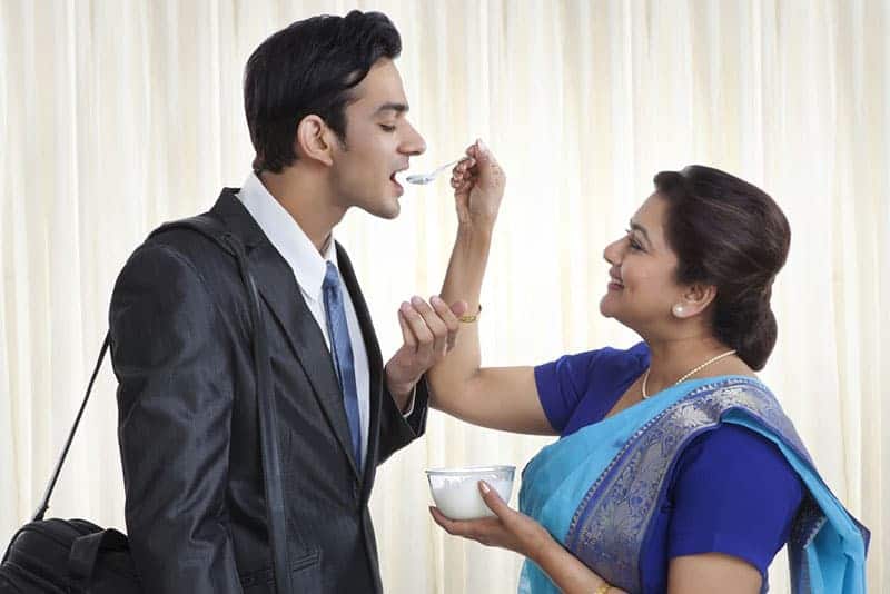 mother giving a spoon of food to her son