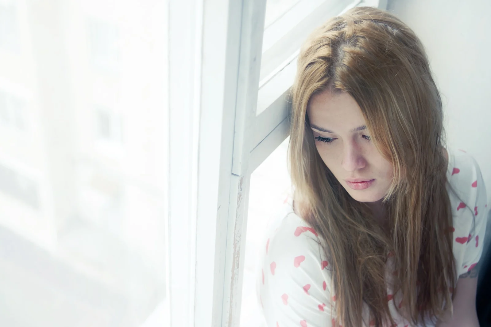 pensive sad woman looking out of window