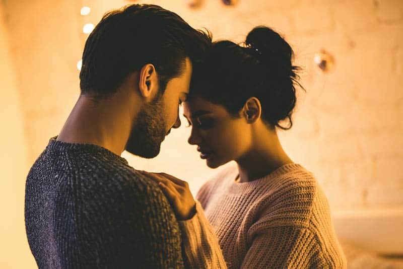 romantic couple standing in front each other with closed eyes at home