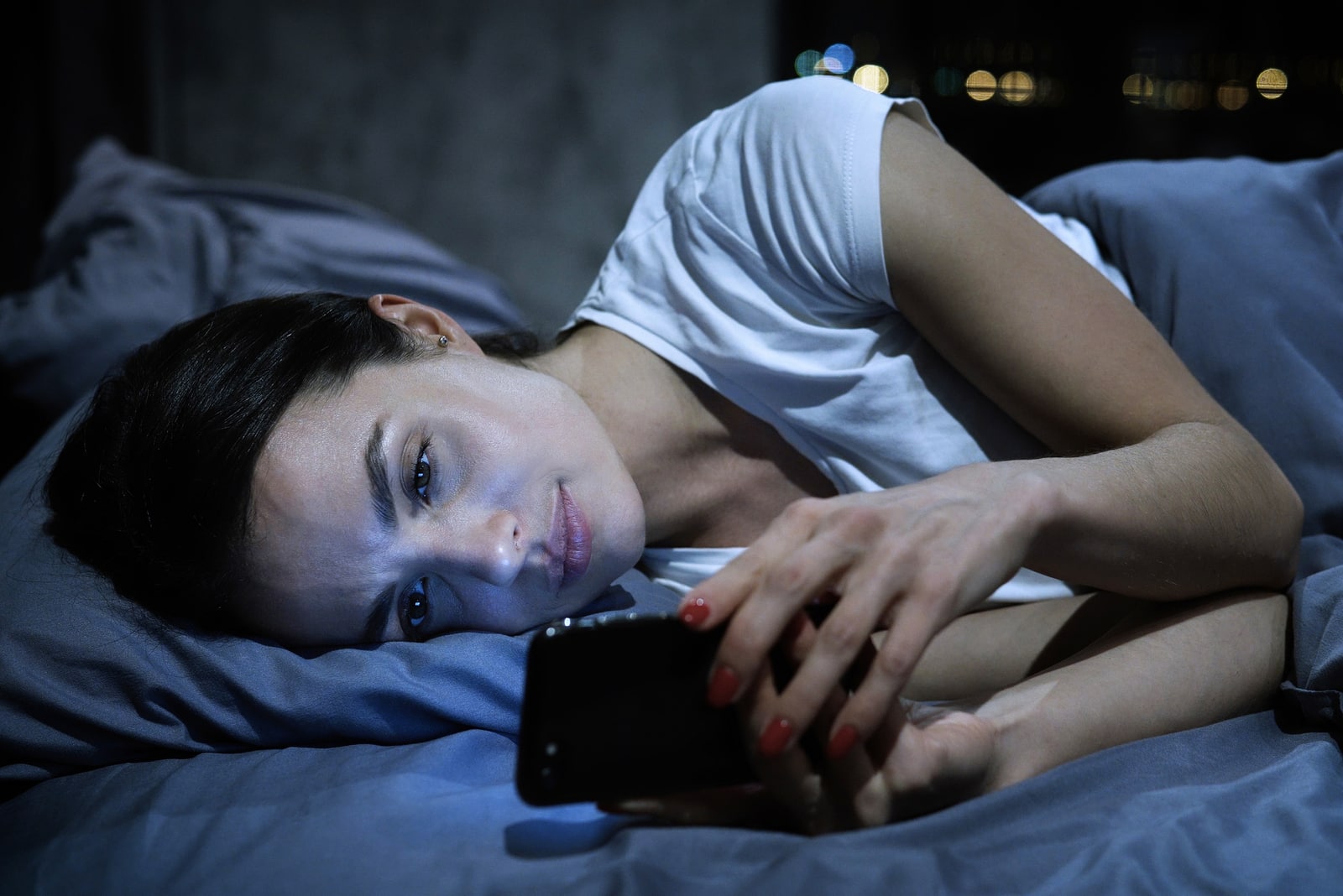 donna triste a letto che messaggia
