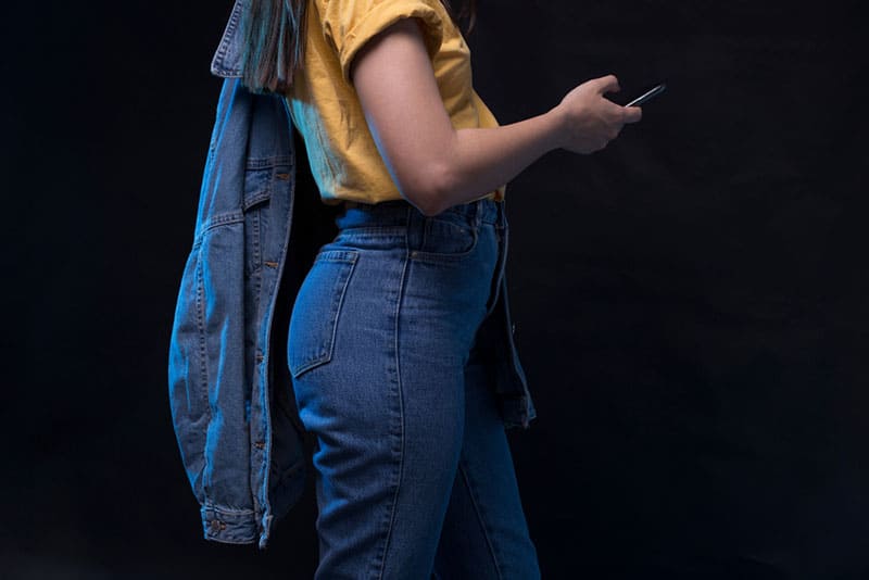 side view of woman wearing jenas with black background