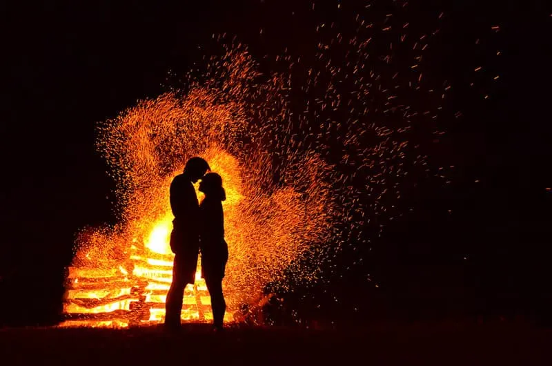 silhouette of man and woman standing beside flame