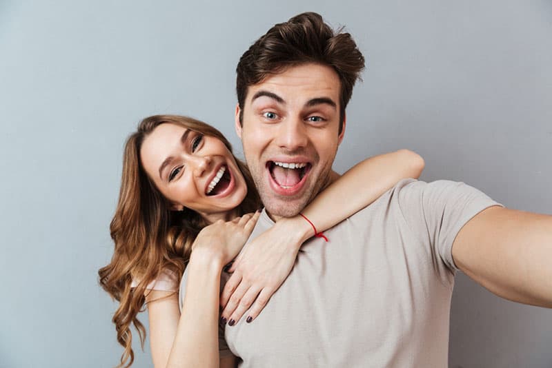 pareja sonriente tomándose un selfie